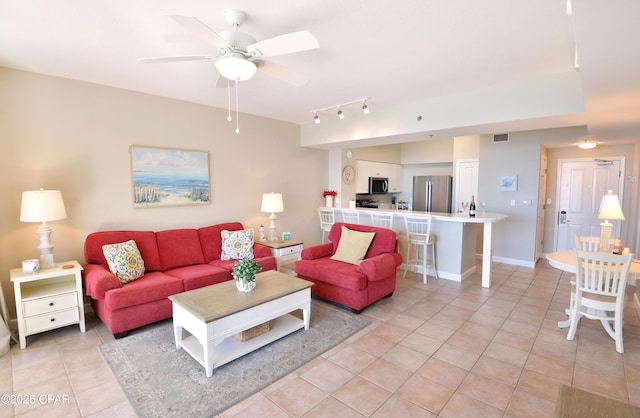 living area featuring light tile patterned floors, a ceiling fan, visible vents, and baseboards