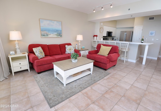 living area with baseboards, visible vents, track lighting, and light tile patterned flooring