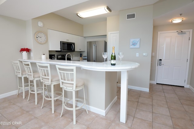 kitchen featuring a peninsula, visible vents, stainless steel appliances, and a kitchen breakfast bar