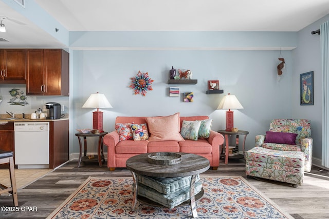 living room with light wood finished floors, visible vents, and baseboards