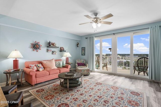 living room with a ceiling fan, baseboards, and wood finished floors