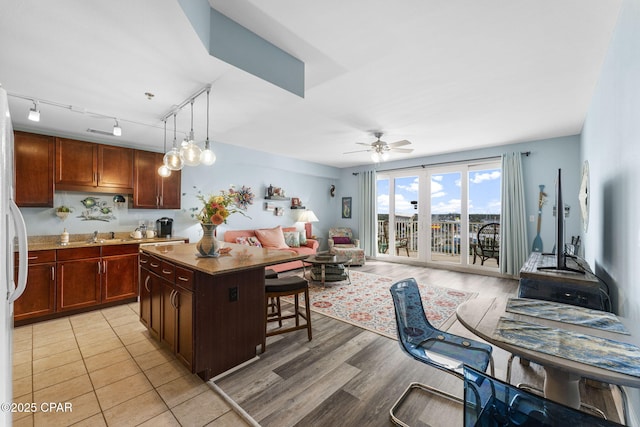 kitchen featuring a center island, decorative light fixtures, open floor plan, ceiling fan, and a kitchen breakfast bar