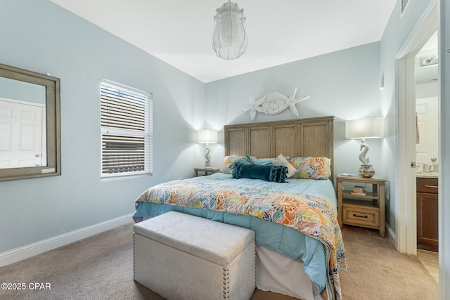 bedroom featuring light carpet, baseboards, and ensuite bathroom