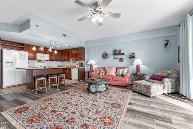 living room featuring a ceiling fan, rail lighting, visible vents, and light wood finished floors