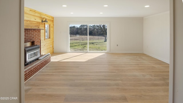 unfurnished living room featuring light wood-style flooring, recessed lighting, wood walls, baseboards, and heating unit