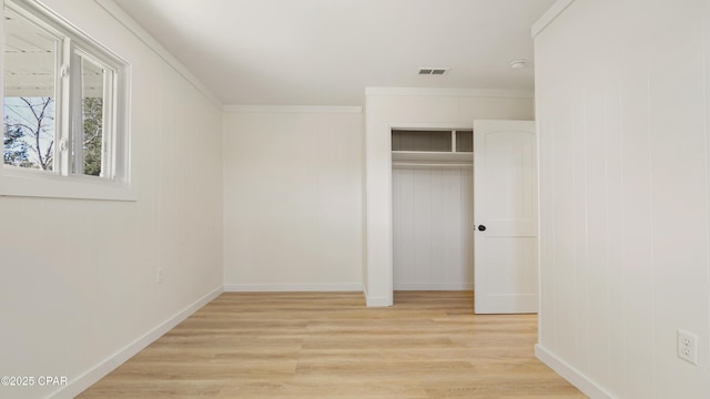 unfurnished bedroom featuring light wood-style flooring, visible vents, baseboards, ornamental molding, and a closet