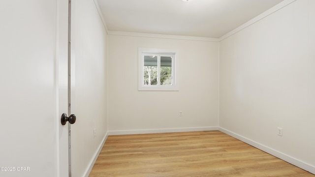 spare room with ornamental molding, baseboards, and light wood finished floors