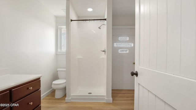 bathroom featuring toilet, a shower stall, wood finished floors, and vanity