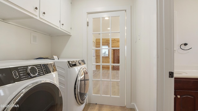 laundry room featuring light wood-style floors, washing machine and dryer, and cabinet space