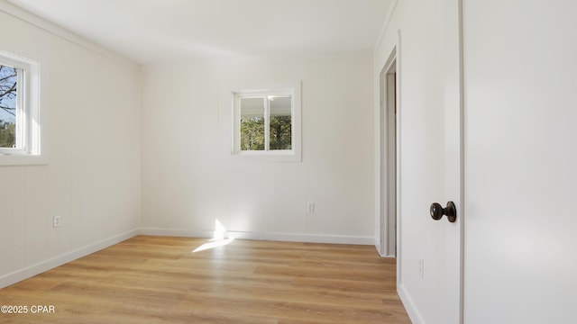 unfurnished bedroom with multiple windows, light wood-style flooring, and baseboards