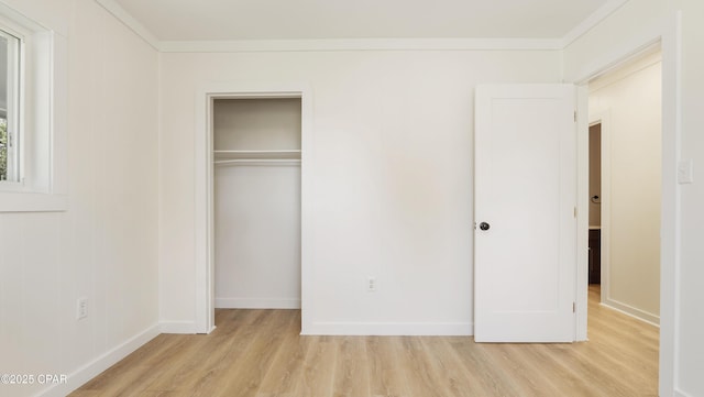 unfurnished bedroom with ornamental molding, light wood-type flooring, a closet, and baseboards