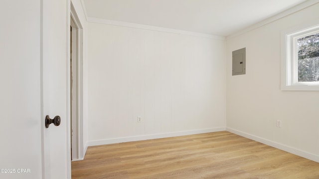 spare room with ornamental molding, baseboards, electric panel, and light wood finished floors