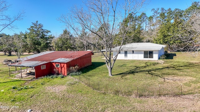 view of yard with fence, a pole building, and an outbuilding