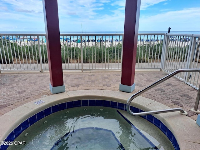 view of pool featuring a view of the beach, a water view, and a hot tub