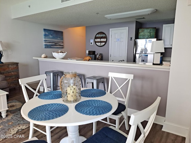 dining space featuring visible vents, baseboards, a textured ceiling, and wood finished floors