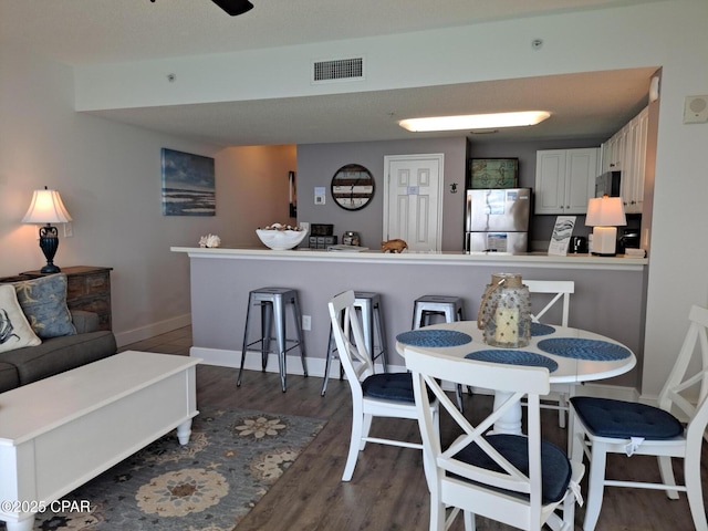 dining space with visible vents, baseboards, and dark wood-style flooring