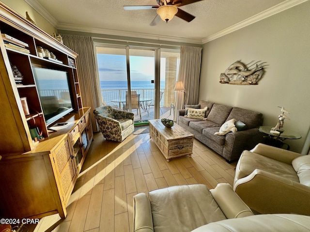 living room with a textured ceiling, ceiling fan, light wood finished floors, and crown molding