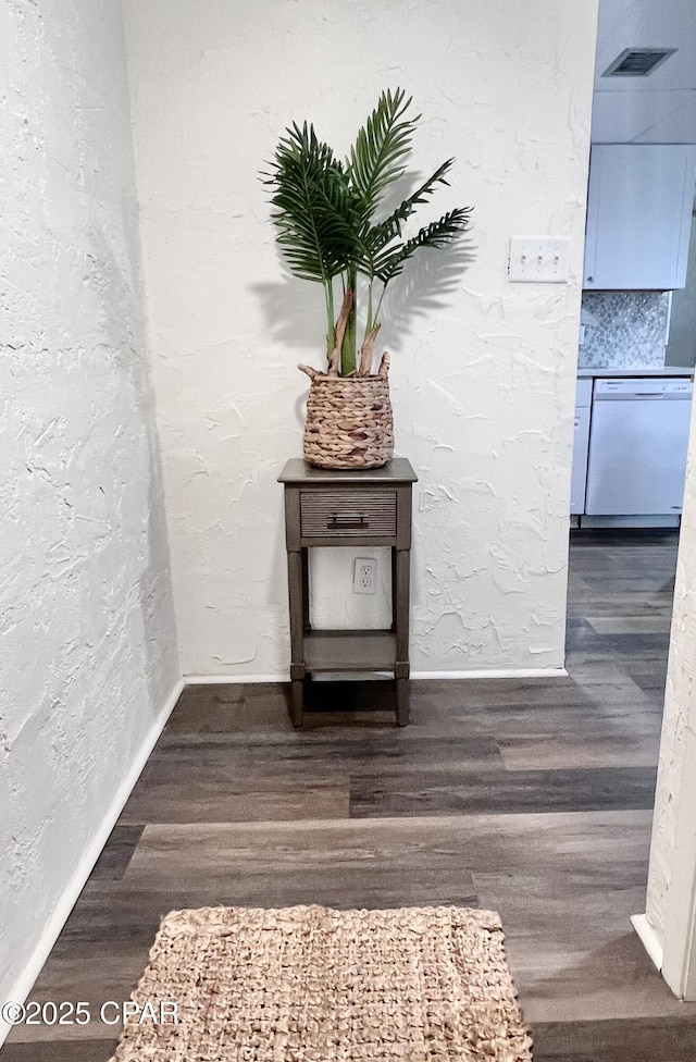 room details featuring a textured wall, white dishwasher, wood finished floors, visible vents, and baseboards