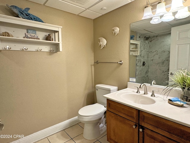 full bath with toilet, tile patterned floors, a tile shower, vanity, and a paneled ceiling