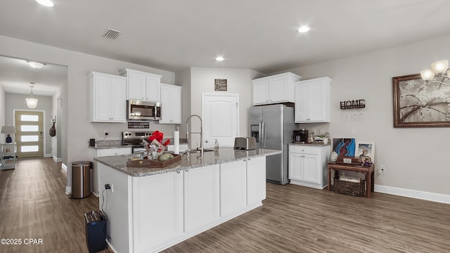 kitchen with dark wood-style flooring, a center island with sink, appliances with stainless steel finishes, and a sink