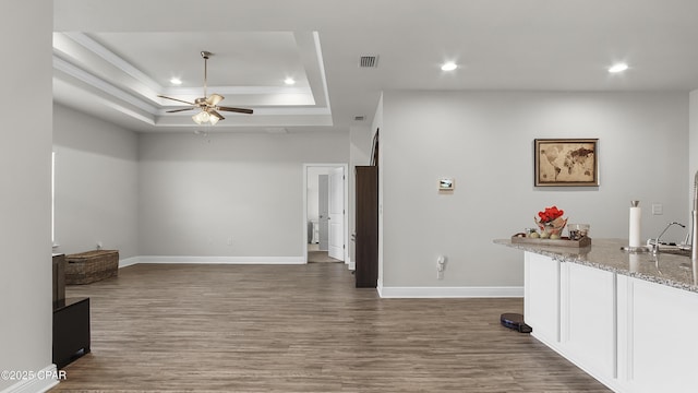 living room featuring ceiling fan, a raised ceiling, wood finished floors, and recessed lighting