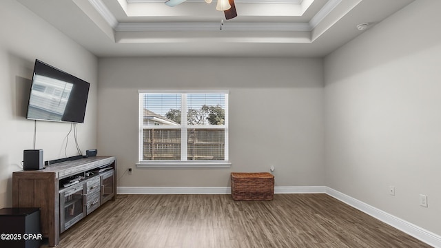 interior space with a raised ceiling, wood finished floors, and baseboards
