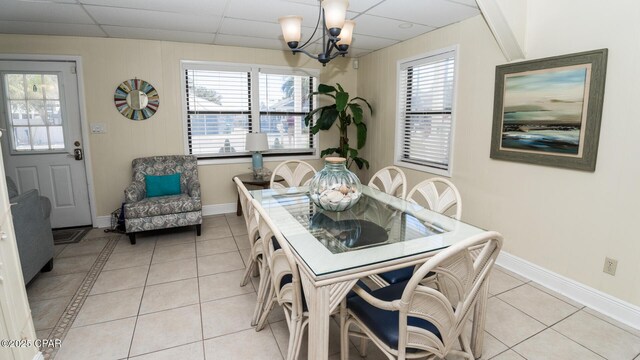 dining area with a notable chandelier, light tile patterned floors, baseboards, and a drop ceiling