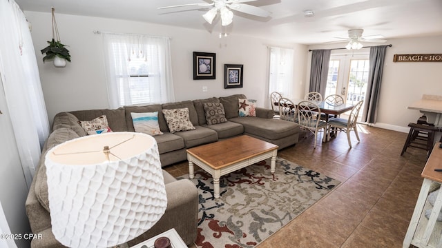 living room featuring dark tile patterned flooring, baseboards, and ceiling fan