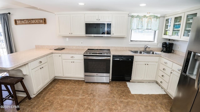 kitchen with a sink, a peninsula, white cabinetry, and stainless steel appliances