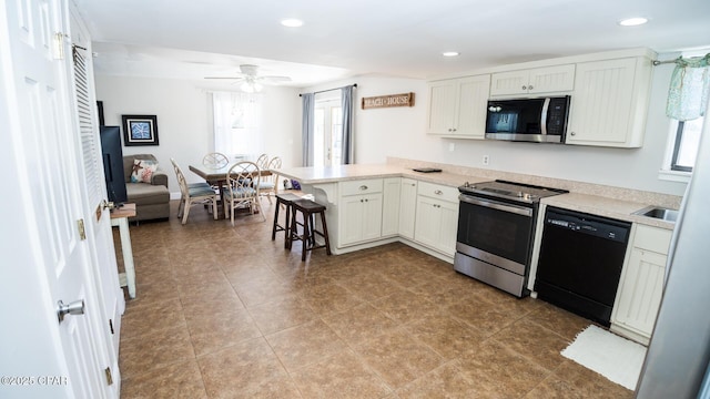 kitchen with a kitchen breakfast bar, stainless steel appliances, a peninsula, light countertops, and ceiling fan