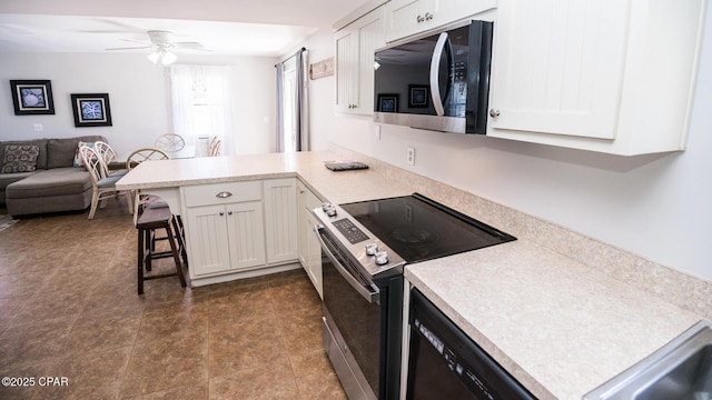 kitchen with a ceiling fan, stainless steel electric range oven, a peninsula, and light countertops