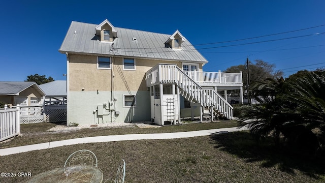 back of property with fence, a wooden deck, stucco siding, stairs, and metal roof