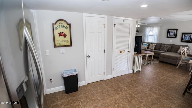 interior space with baseboards, a ceiling fan, and stainless steel refrigerator with ice dispenser