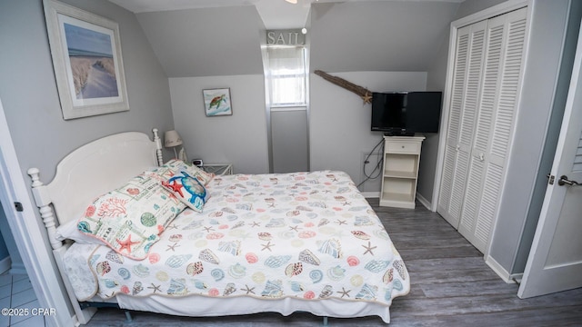 bedroom featuring a closet, baseboards, dark wood-type flooring, and vaulted ceiling