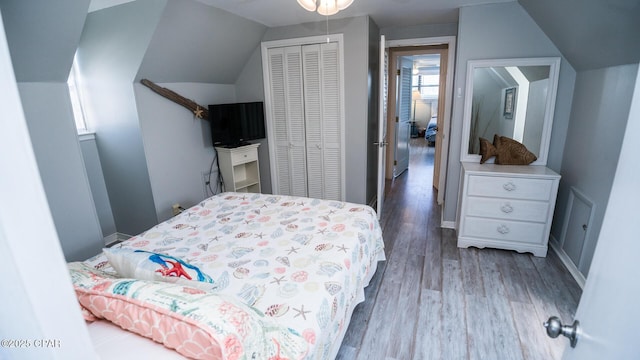 bedroom featuring a closet, baseboards, lofted ceiling, and wood finished floors