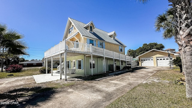 view of front of house with stucco siding, an outbuilding, metal roof, and concrete driveway