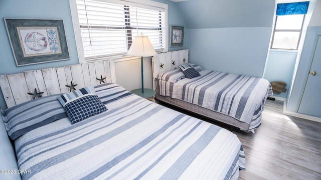 bedroom with vaulted ceiling and wood finished floors