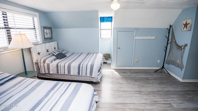 bedroom with a textured ceiling, lofted ceiling, baseboards, and wood finished floors