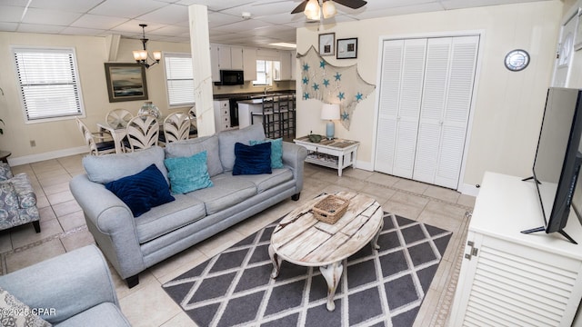 living room with light tile patterned floors, a drop ceiling, baseboards, and a ceiling fan