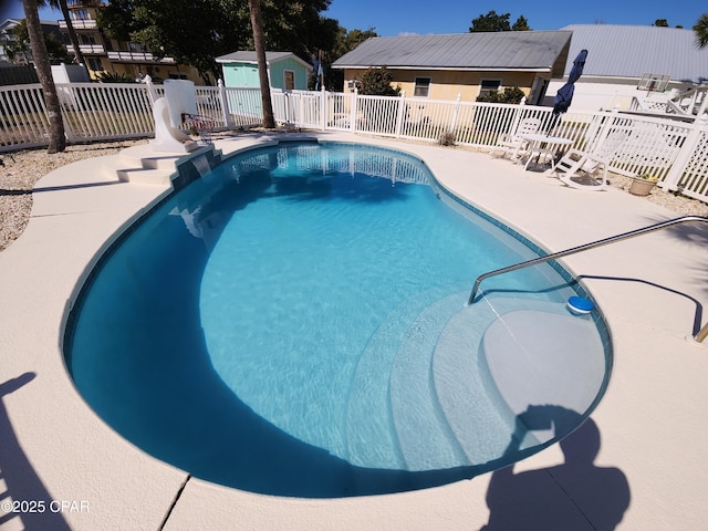 view of swimming pool featuring a fenced in pool, an outbuilding, a patio area, and fence