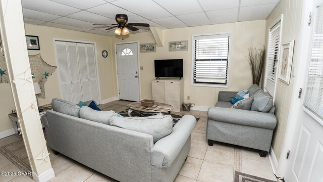 living room with baseboards, a paneled ceiling, ceiling fan, and light tile patterned flooring