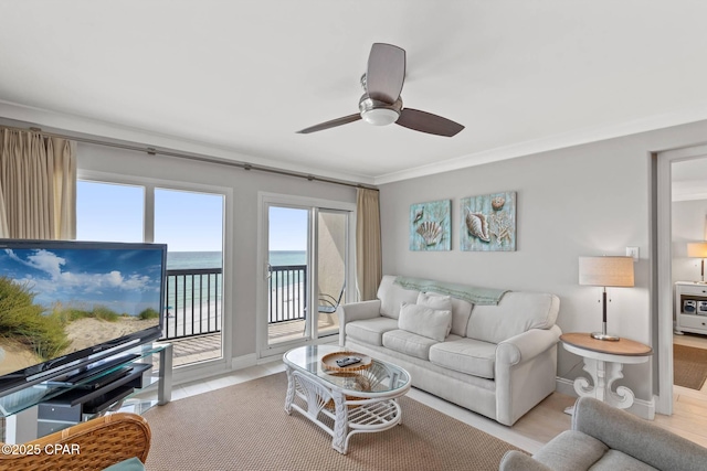 living room featuring ornamental molding, a ceiling fan, and baseboards