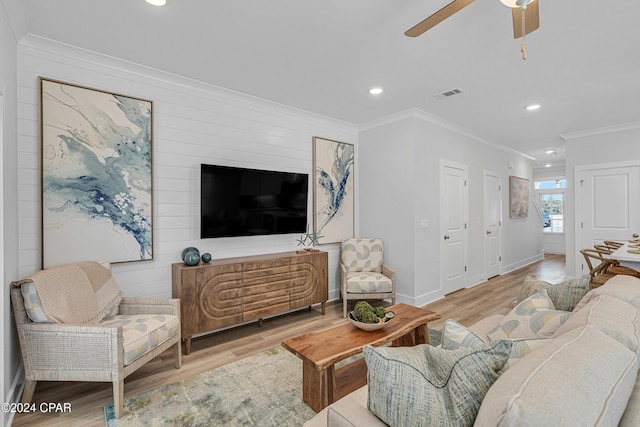 living room featuring ornamental molding, visible vents, baseboards, and wood finished floors