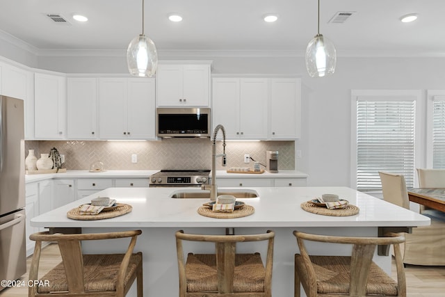 kitchen featuring a sink, visible vents, light countertops, ornamental molding, and appliances with stainless steel finishes