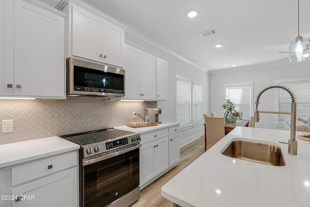 kitchen featuring visible vents, decorative backsplash, appliances with stainless steel finishes, ornamental molding, and a sink