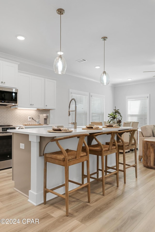 kitchen featuring stainless steel appliances, crown molding, backsplash, and light wood-style flooring