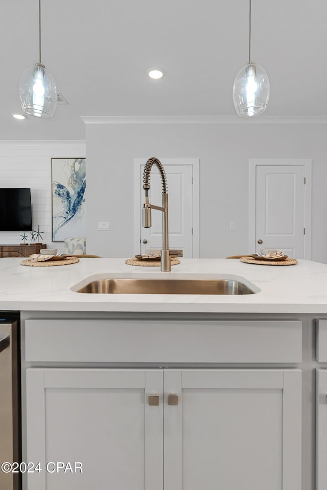 kitchen featuring ornamental molding, hanging light fixtures, a sink, light countertops, and stainless steel dishwasher