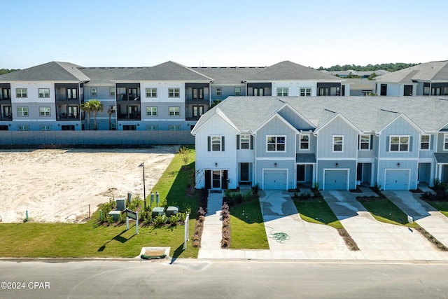 view of property featuring driveway, a garage, a residential view, board and batten siding, and a front yard