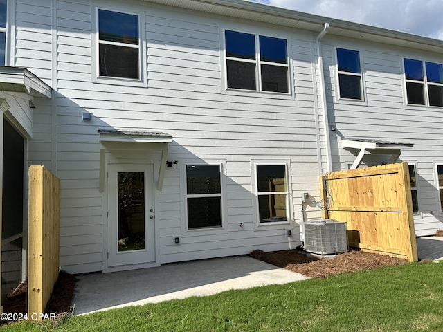 rear view of house featuring fence, central AC unit, and a patio