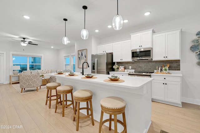 kitchen with a breakfast bar area, tasteful backsplash, light countertops, appliances with stainless steel finishes, and light wood-type flooring